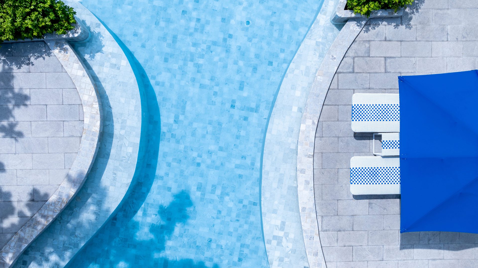An aerial view of a Cape Town poolside with an umbrella beside clear blue water